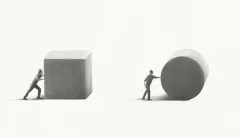 Immagine: ritrae due figure umane che spingono due enormi solidi geometrici, un cubo e un cilindro