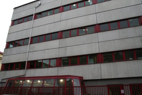 Edificio grigio con profili delle finestre rossi, cancellata rossa