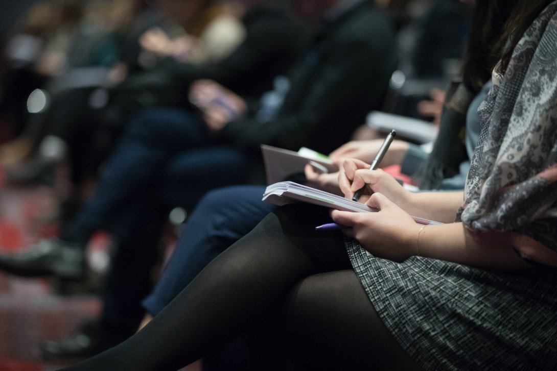 Foto di persone sedute che prendono appunti su dei bloc notes