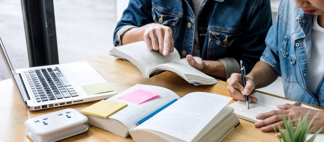 Studente che ne aiuta un altro, computer e libri